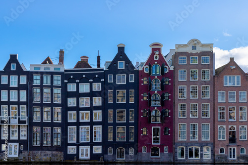 Architecture features traditional houses with blue sky  Typical dutch house at Damrak canal  An avenue running between Amsterdam Centraal in the north and Dam Square in the south  Holland  Netherlands