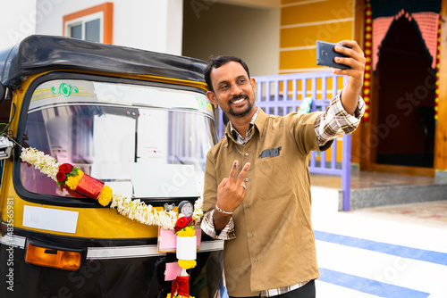 Auto driver taking selfie with his auto rickshaw to post on social media about new business - concept of self employment and transportation service