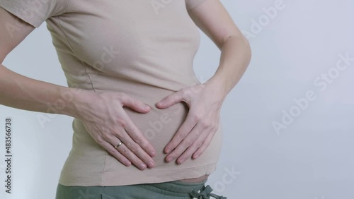 a pregnant girl strokes her belly and forms a heart from her hands. waiting for the baby, maternal love. there is a copy space on a white background.