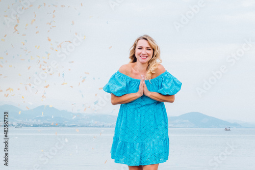 Happy young woman celebrating at beach party. Portrait of a girl with birthday confetti
