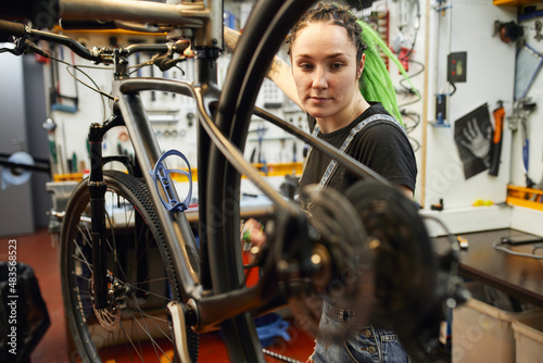 Female mechanic repairing bicycle in workshop