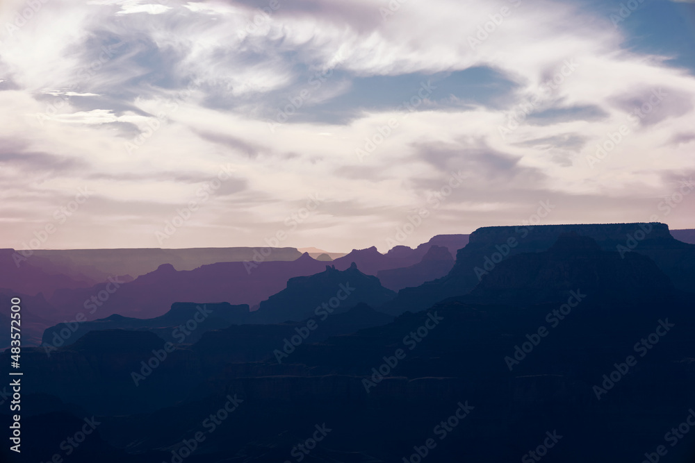 Purple desert mountains against a cloudy sky of cirrus clouds