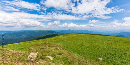 green summer landscape in mountains. outdoor scenery with blue sky and clouds. beautiful nature backgroun on a sunny day. stones on the grassy hill