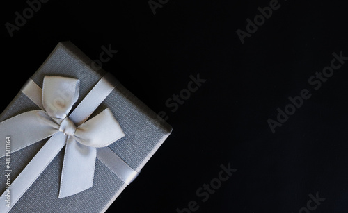 Big day gift, grey gift box with luxury bow on dark background with copy space.