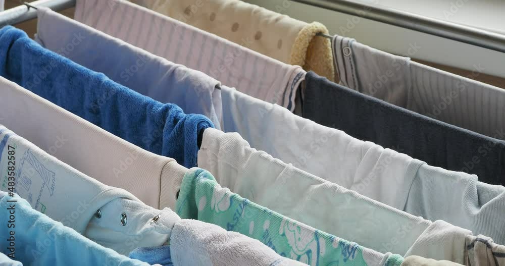 purely washed baby clothes for a newborn, hung on the dryer Stock Video