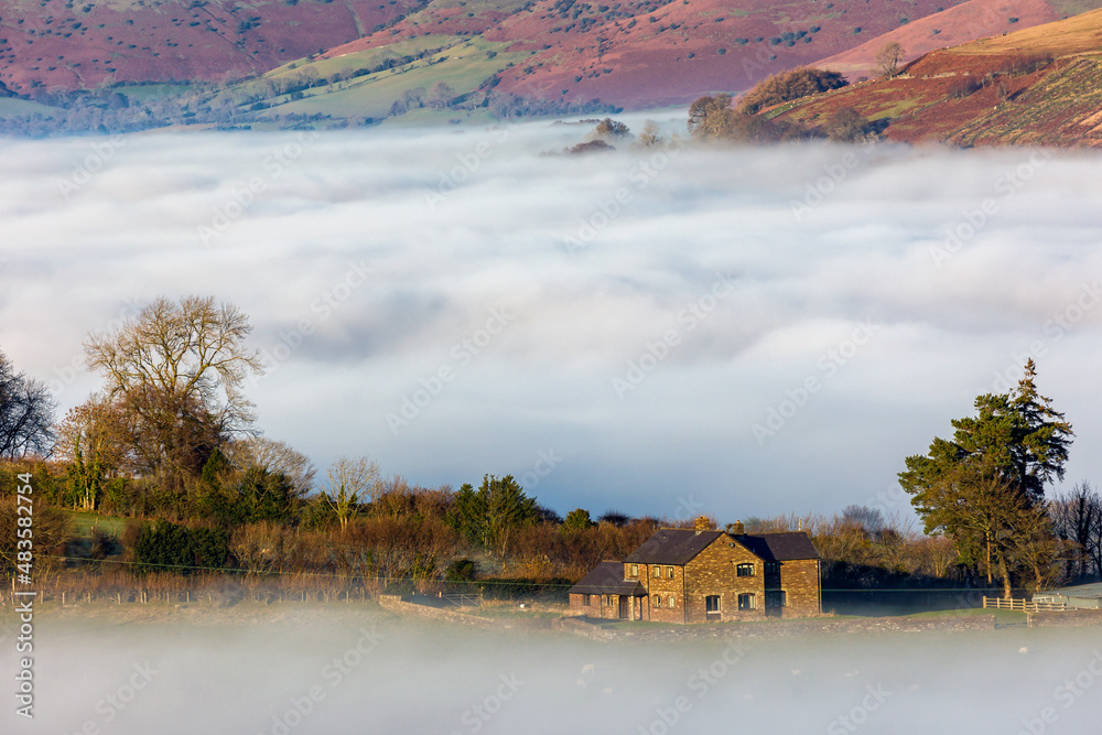 Fototapeta premium Farmland above low lying fog and a cloud inversion in the Brecon Beacons, Wales