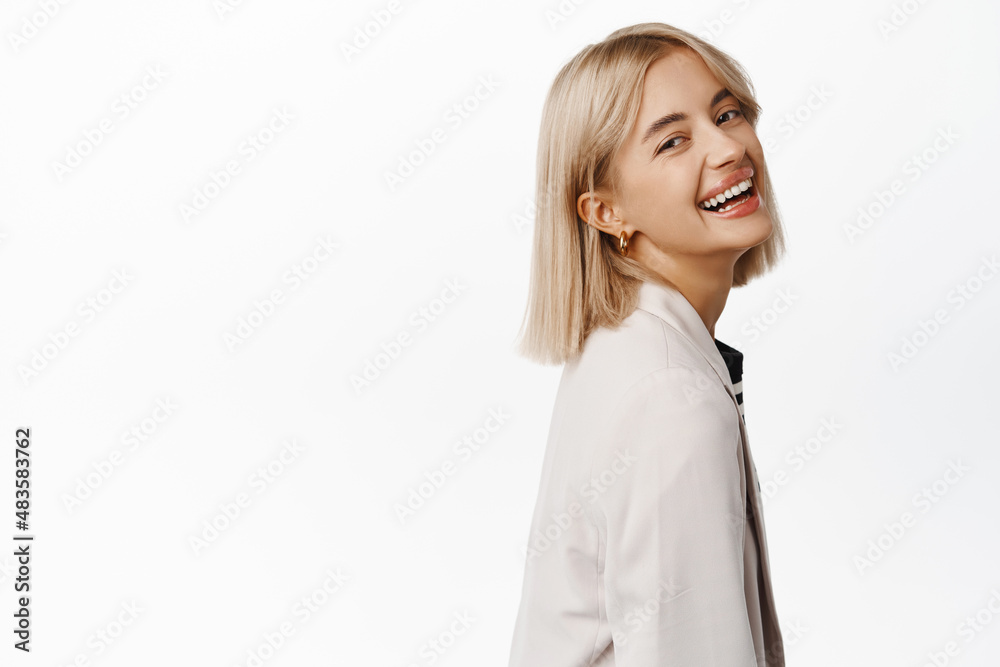 Close up of confident young professional business woman, turn head at camera, standing in profile, smiling and laughing, showing her professionalism and confidence Close up of confident young professional business woman, turn head at camera, standing in profile, smiling and laughing, showing her professionalism and confidence