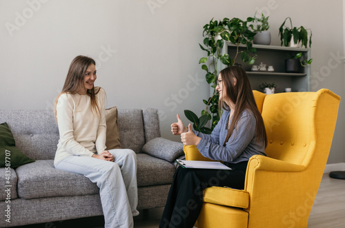 a satisfied female patient is sitting on the couch at a psychologist's appointment. Successful course of psychotherapy photo