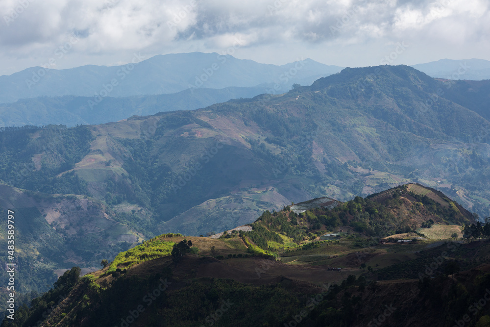 Dramatic image of farms and agricultural fields high in the Caribbean mountains. With fading mountains in the background, in the Dominican Republic.