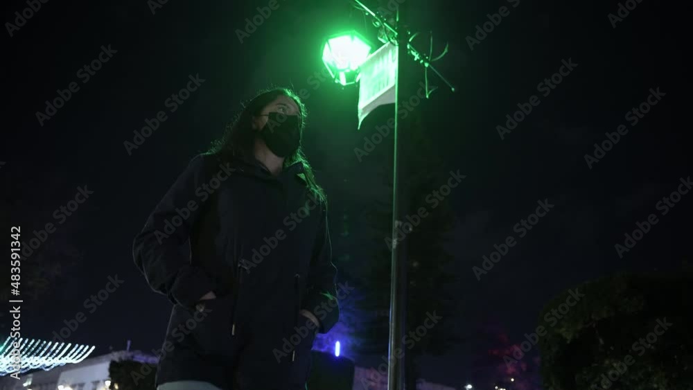 Woman standing next to a lamp post at night Woman standing next to a lamp post at night