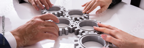 Businesspeople Joining Gears On Desk