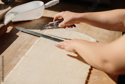 Woman baker cuts the dough into triangles for croissants. Making croissants in the bakery.