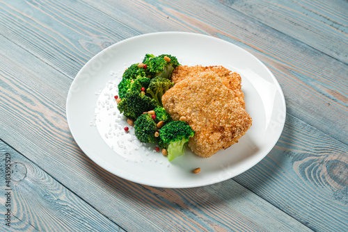 Crispy fresh fish with broccoli served on the plate on the wooden table