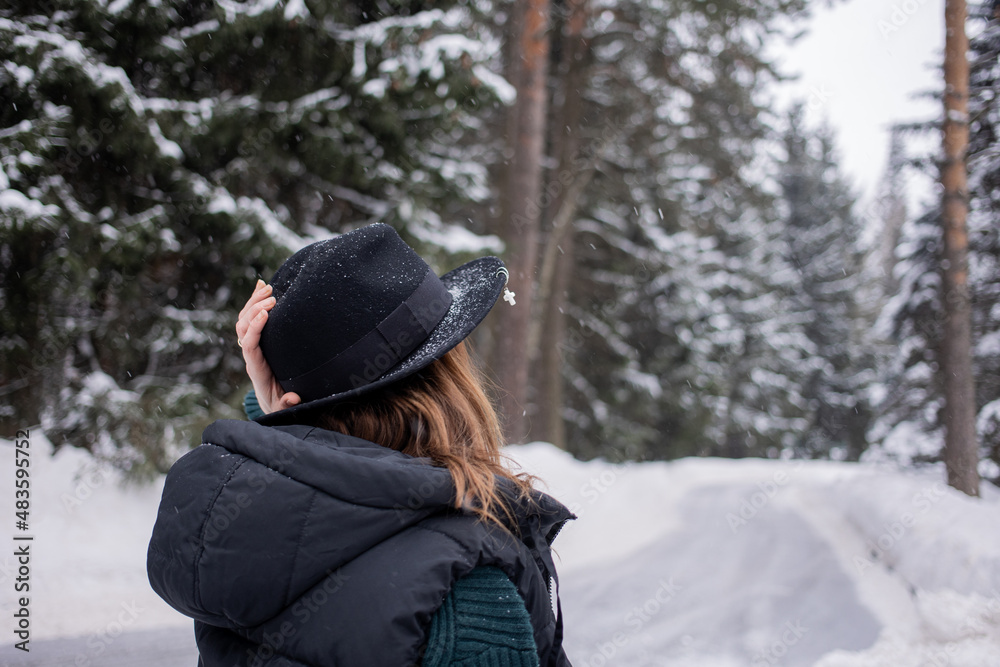 Caucasian young woman in black hat in winter snowy forest. Caucasian young woman in black hat in winter snowy forest.