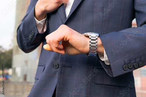 Young entrepreneur sitting looking at the time on his watch.