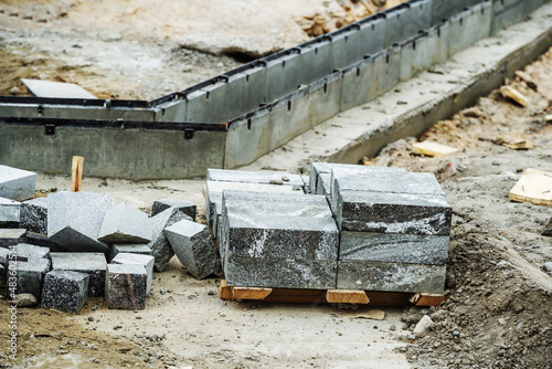 Construction of a drainage system. Concrete gutter and granite pavers are located at the construction site. Selective focus. Foreground