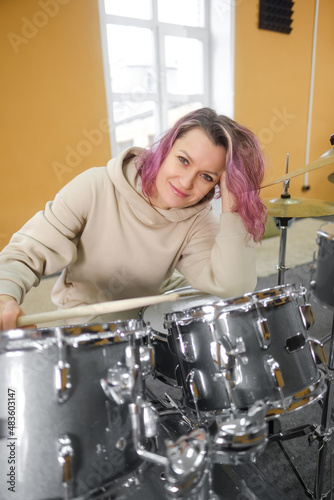 Portrait of a young beautiful adult woman behind a drum kit. Hobbies and pastime.