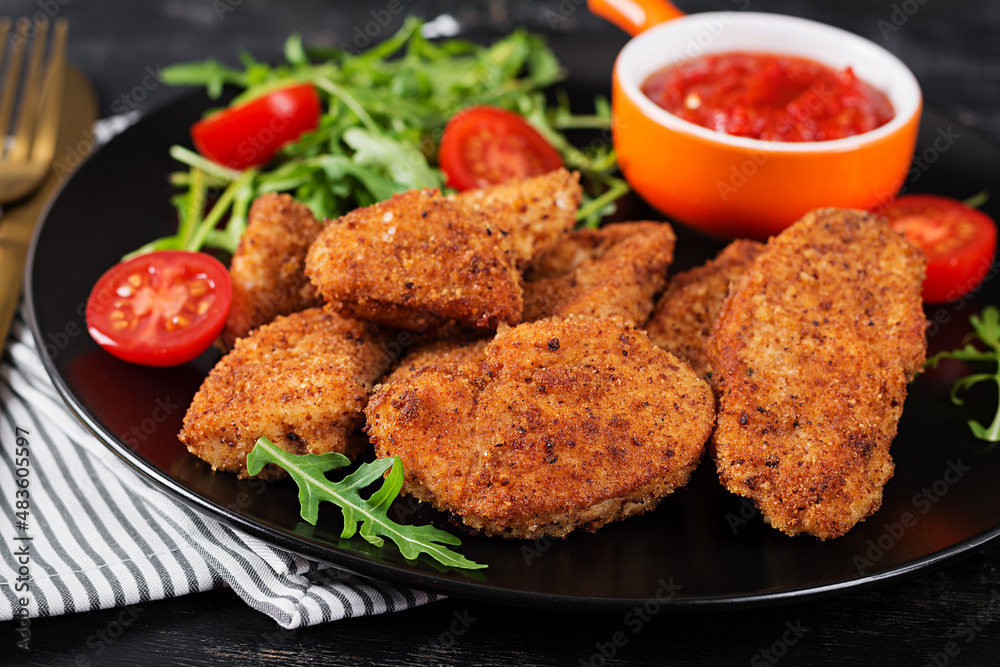 Chicken nuggets and sauce in black plate on a dark background. Chicken nuggets and sauce in black plate on a dark background.