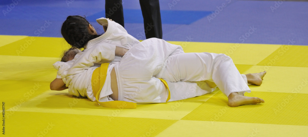 Two Girls judoka in kimono compete on the tatami Two Girls judoka in kimono compete on the tatami