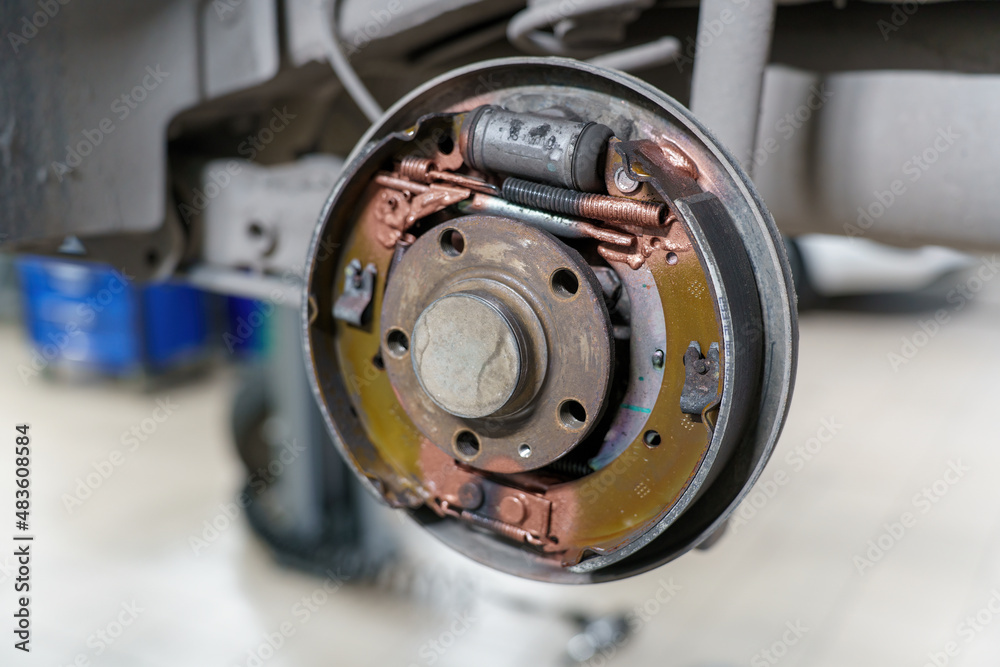 Automotive transmission. Rear brake drum. Maintenance and lubrication in garage on lift.