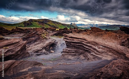 Stunning Iceland nature landscape.  Scenic Image of Iceland. red sandy Volcanic rock formation near Dyrholaey coast of Iceland, Europe. Typical Icelandic scenery in a cloudy day. © jenyateua