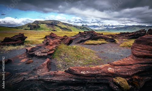 Stunning Iceland nature landscape. Scenic Image of Iceland during sunset. Red sandy Volcanic rock formation near Dyrholaey coast of Iceland, Europe. Typical Icelandic scenery in a cloudy day.