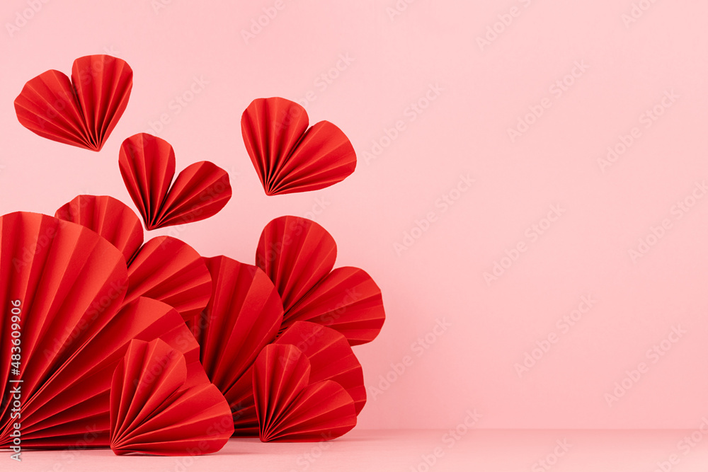Valentines day scene in asian style - fly red paper hearts on pastel pink color, border, copy space, closeup. Romantic stage mockup for presentation cosmetic product, goods, card, poster, flyer.