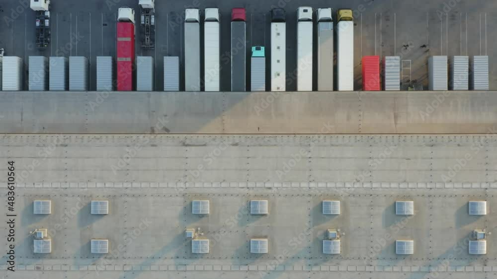 Aerial top down view of cargo semitrailers standing on warehouse ramps for loading and unloading goods in the logistics park