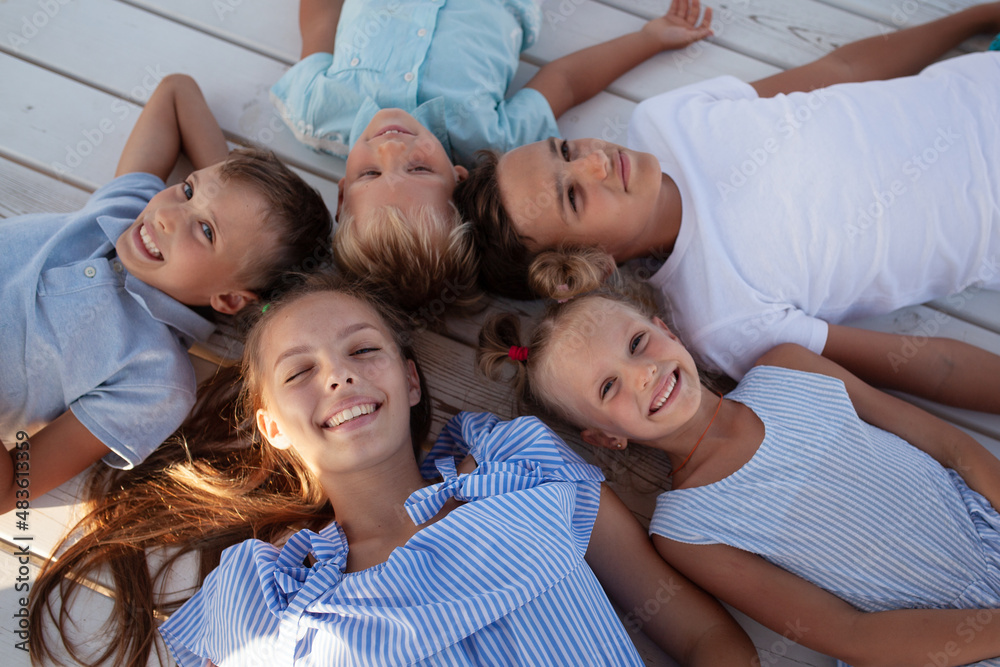 Portrait of happy children, girls and boys lie with their heads to the center