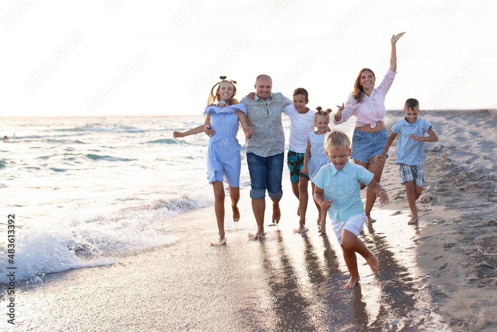 portrait of a big happy family, parents with children are relaxing on the seashore