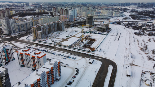 Construction site of a modern city block. High-rise buildings under construction. Construction tower cranes. Construction site in winter. Aerial photography at sunset.