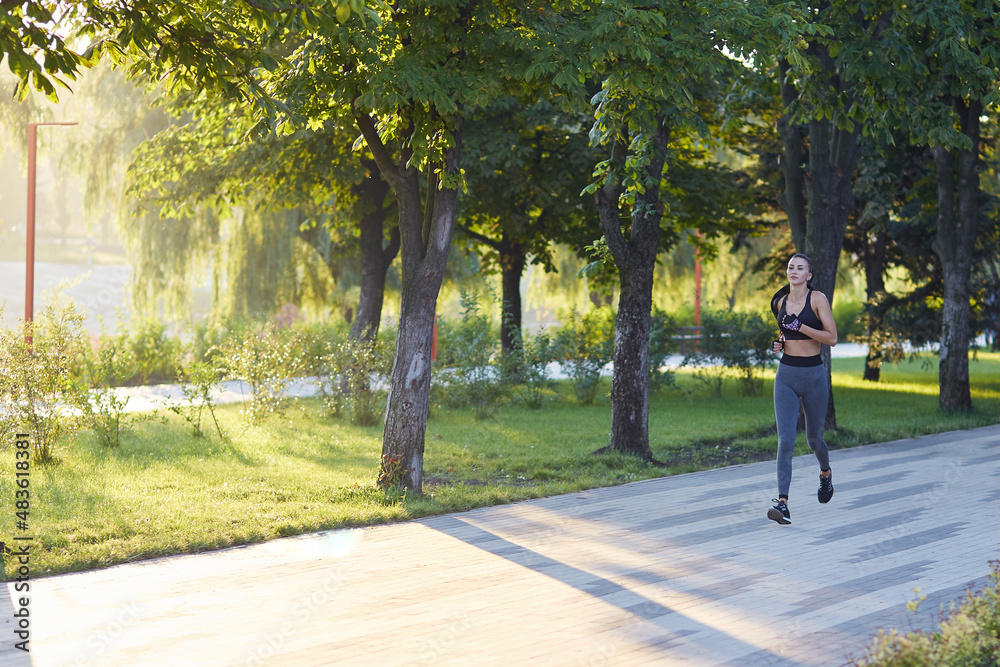 Morning jogging, young fitness lady. Workout in the park outdoors