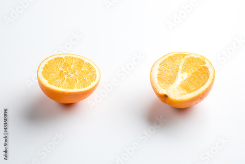 Two halves of an orange on a white background. One is cut lengthwise, the other across