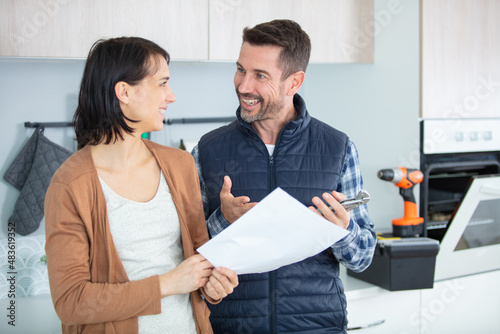 female client and repairman smiling signing contract