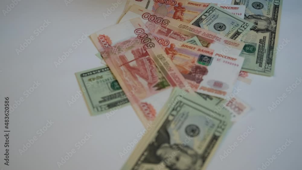 American money and Russians take turns tossing onto the white table. Five thousandth Russian rubles and twenty and one hundred dollar bills of the USA are taken out of the pack American money and Russians take turns tossing onto the white table. Five thousandth Russian rubles and twenty and one hundred dollar bills of the USA are taken out of the pack