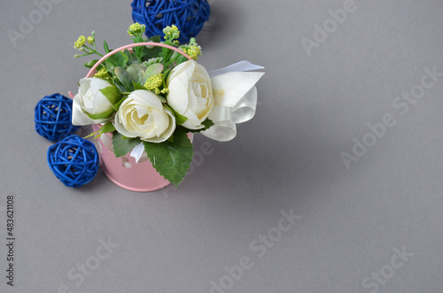 Decorative flowers in a bucket and blue balls on a gray background. photo