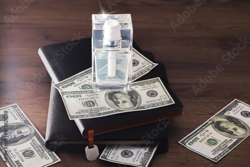 A bottle of men's perfume, a notebook and dollar bills. Men's gift concept.