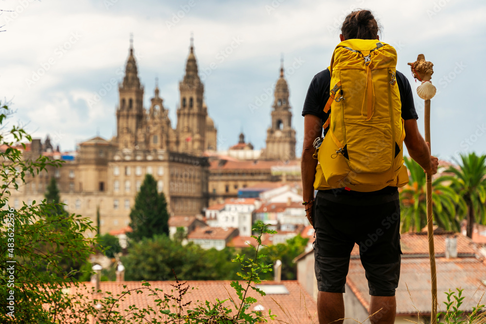 pilgrim looking at the cathedral of Santiago de Compostela in Spaink, backpack on his back. - obrazy, fototapety, plakaty 