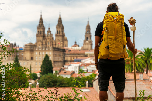 Leinwand Poster pilgrim looking at the cathedral of Santiago de Compostela in Spaink, backpack on his back