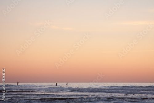 paddle boarders on the ocean at sunset © Sally