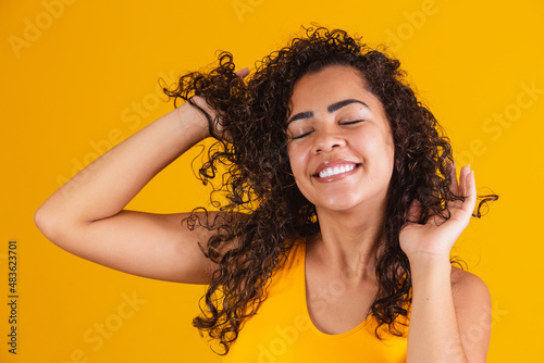 Fotografie Happy laughing African American woman with her curly hair on yellow background