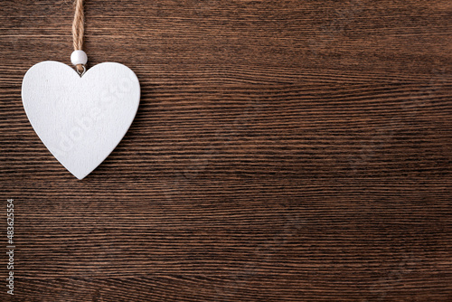 White wooden heart on a wooden background. Neutral brown background. Eco concept for valentine's day