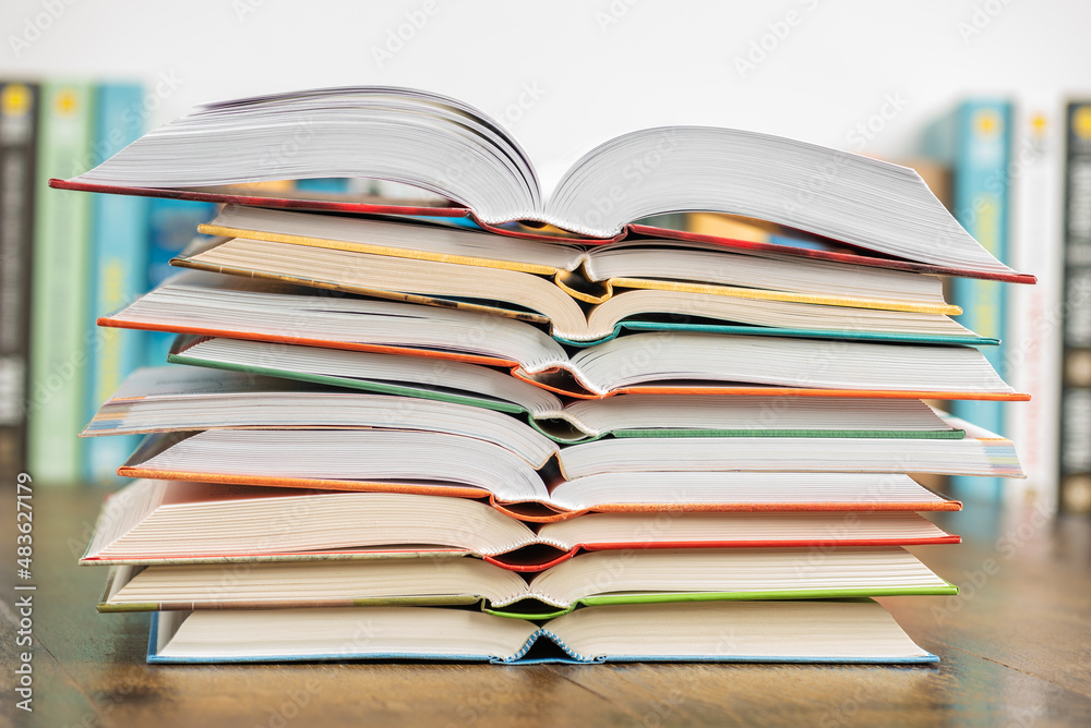Stack opened book on wooden desk with blurred soft library background Stack opened book on wooden desk with blurred soft library background