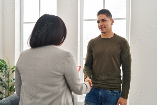 Man and woman having psychology session shake hands at clinic