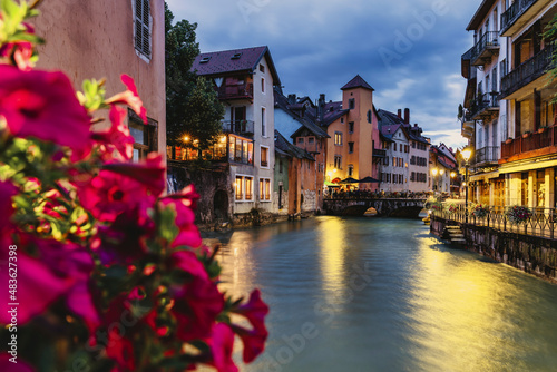 city ​​view of Annecy in France at night on the banks of the river, with flowers in the foreground - Selective focus.