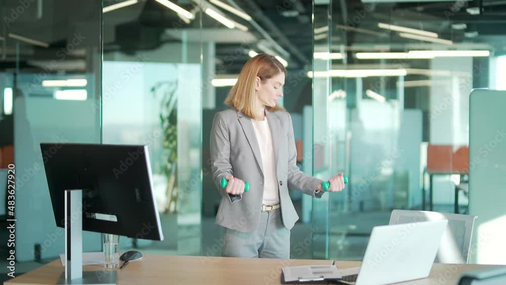 Woman office worker doing exercises with dumbbells in modern office in front laptop computer. Business Female fitness executive employee in the workplace Healthcare. break a healthy lifestyle. Online Woman office worker doing exercises with dumbbells in modern office in front laptop computer. Business Female fitness executive employee in the workplace Healthcare. break a healthy lifestyle. Online