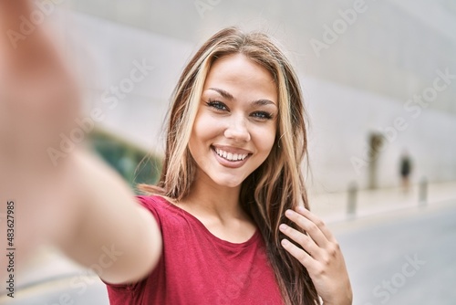 Young caucasian girl smiling happy making selfie by the camera at the city. Free Download Young caucasian girl smiling happy making selfie by the camera at the city. - GFXLoad