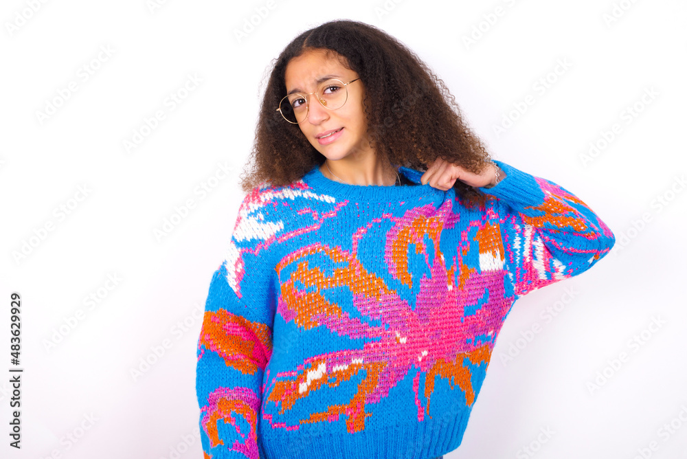 African teenager girl wearing colorful sweater over white background stressed, anxious, tired and frustrated, pulling shirt neck, looking frustrated with problem African teenager girl wearing colorful sweater over white background stressed, anxious, tired and frustrated, pulling shirt neck, looking frustrated with problem