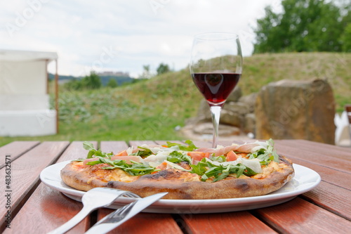 Pizza spezial mit einem Glas Rotwein im Biergarten