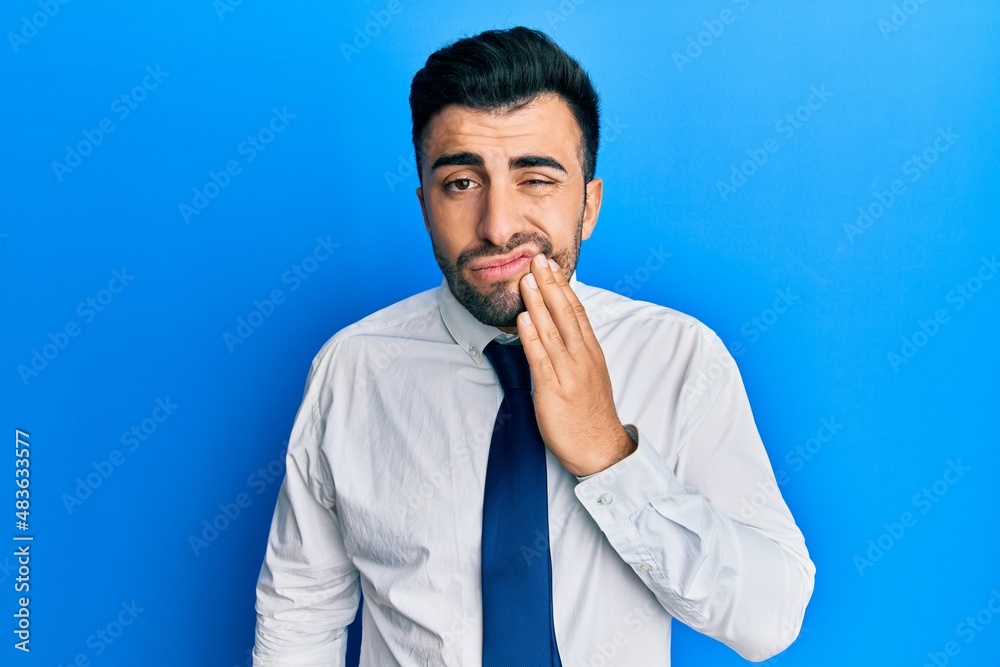 Young hispanic man wearing business clothes touching mouth with hand with painful expression because of toothache or dental illness on teeth. dentist Young hispanic man wearing business clothes touching mouth with hand with painful expression because of toothache or dental illness on teeth. dentist